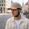 Close-up van man met beige fietshelm met pet en hertenlogo en Vero bandje zichtbaar